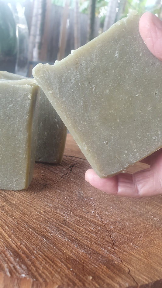 Organic Cucumber & Aloe Vera Tallow Soap held above wooden surface with additional bars behind.